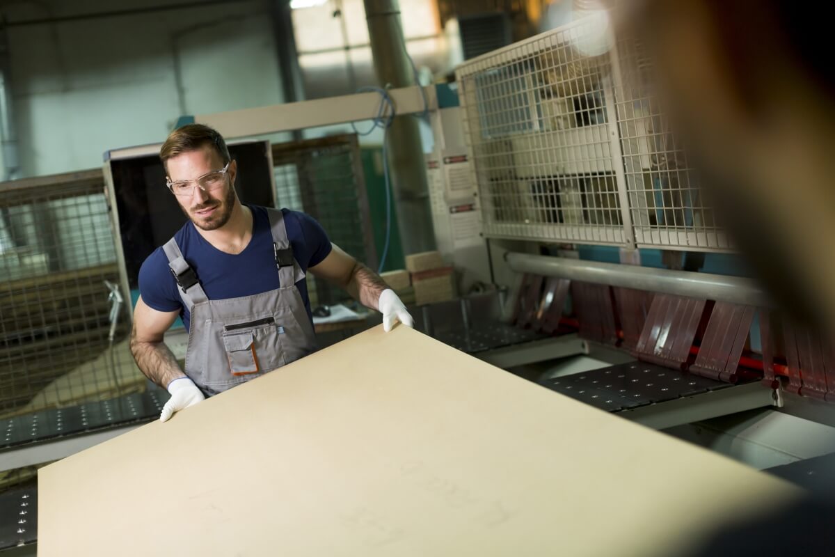 Pracownik produkcji w zakładzie, gdzie działa producent sklejki.